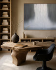 Modern home office with wooden desk, black chair, and abstract painting on wall.