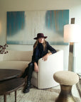 Woman in a hat sitting on a couch in a modern living room.