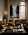 A large, black and white photograph of a natural scene, featuring a body of water with a powerful, flowing current, displayed on a wall in a nicely furnished living room setting with leather chairs and a glass coffee table.