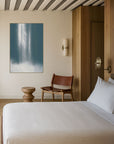 Bedroom with a bed, chair, and wall art on a striped ceiling.