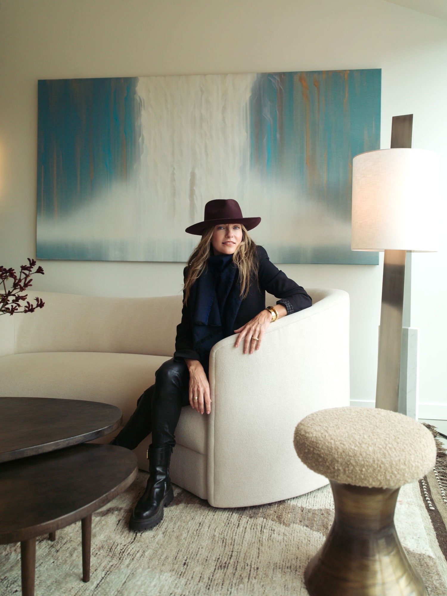 Woman in a hat sitting on a couch in a modern living room.