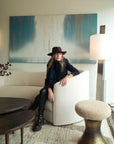 Woman in a hat sitting on a couch in a modern living room.