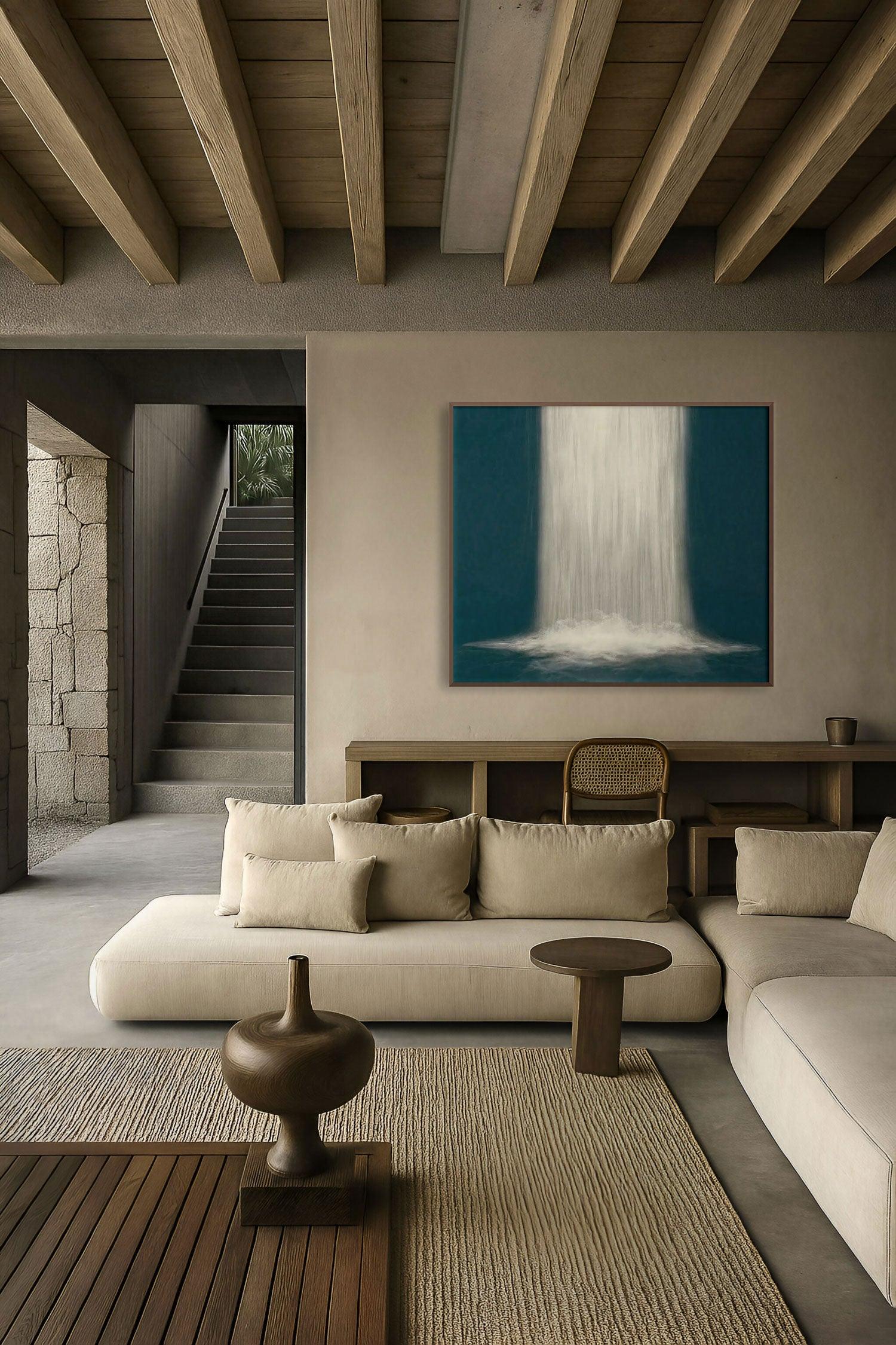 A painting with abstract blue lines displayed above a beige sofa in a room with wooden beams and a stone staircase in the background.