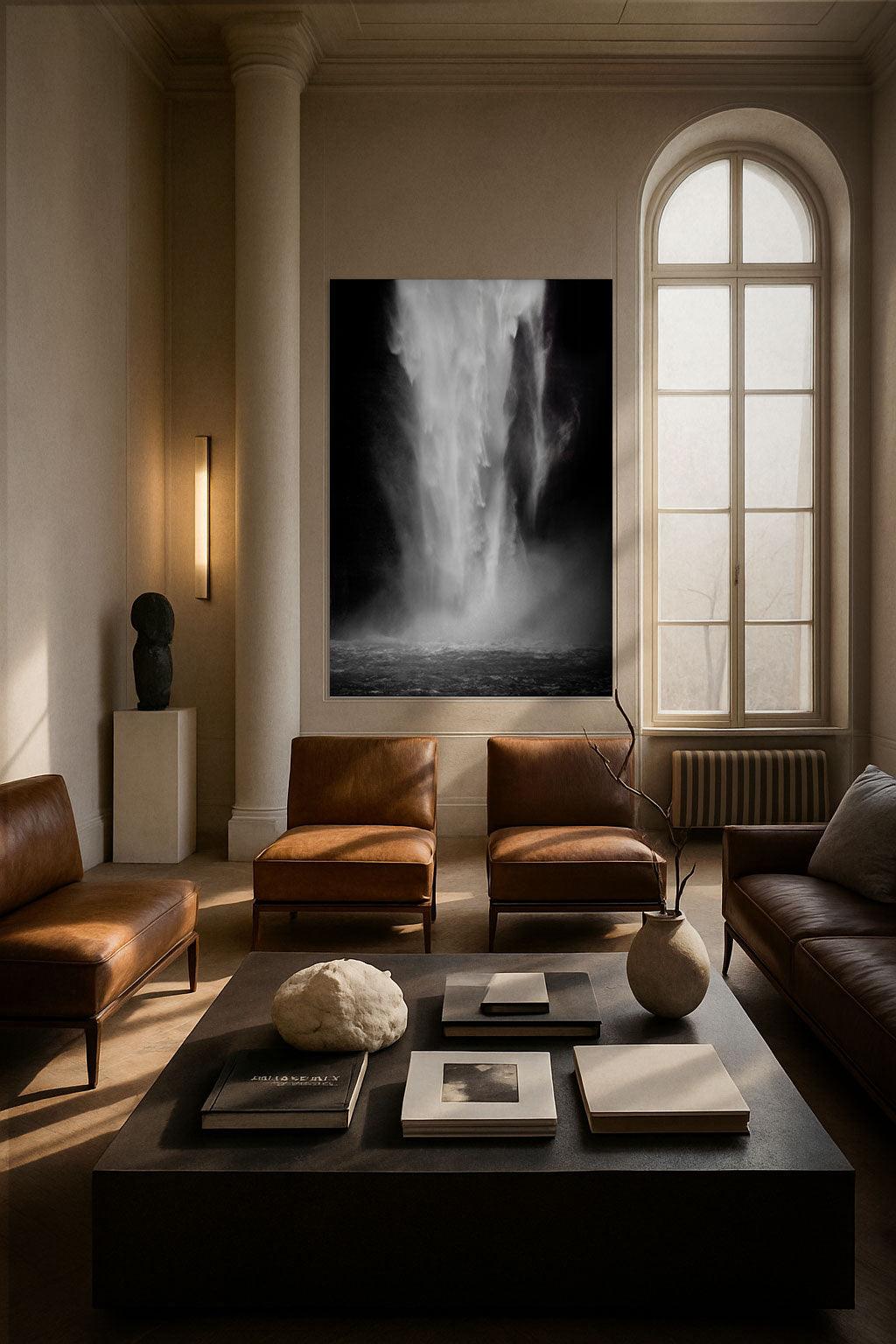 A large, black and white photograph of a natural scene, featuring a body of water with a powerful, flowing current, displayed on a wall in a nicely furnished living room setting with leather chairs and a glass coffee table.