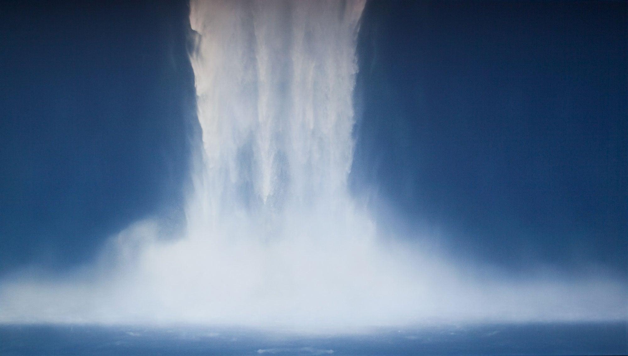 A framed print of a waterfall, with a predominantly blue color palette, displayed against a dark background.