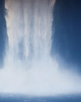 A framed print of a waterfall, with a predominantly blue color palette, displayed against a dark background.