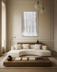 A minimalist living room with a large window, white sofa, and a abstract white artwork hanging on the wall.